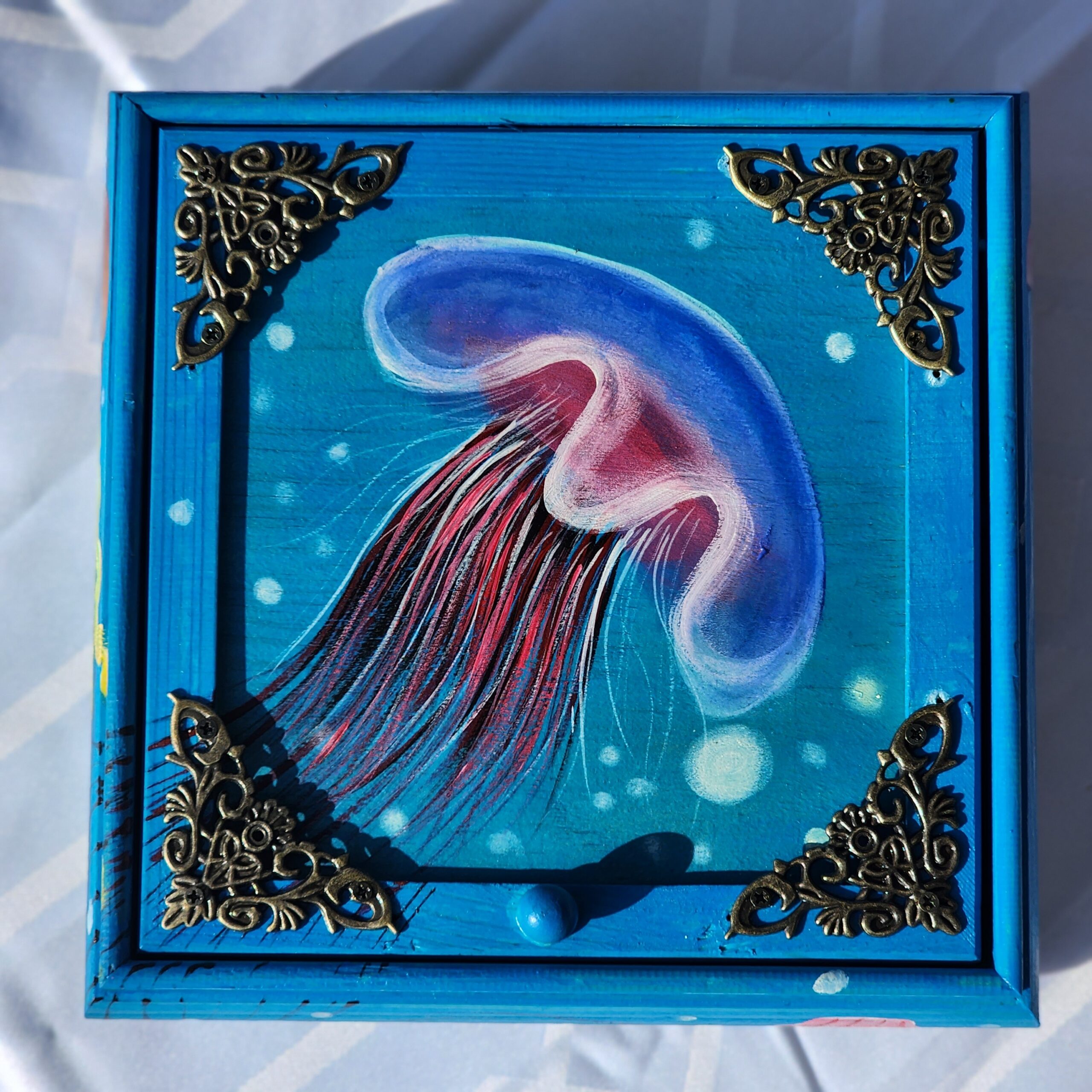 Beautiful handpainted wooden trinket box with a mirror, decorative hardware and metal feet. This cute jellyfish trinket box is an ideal gift for a special loved one. You can store jewelry such as rings, necklaces, bracelets, or anything you would like to keep in a particular place, especially in this elegant and artistic trinket box.