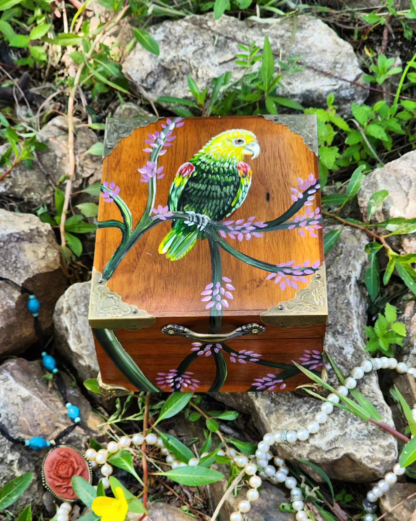 Antique wooden jewelry box with original design of a Yellow Headed Amazon. This box includes hard plastic feet, bronze handle, bronze decorative corners, and red pad insert ring.