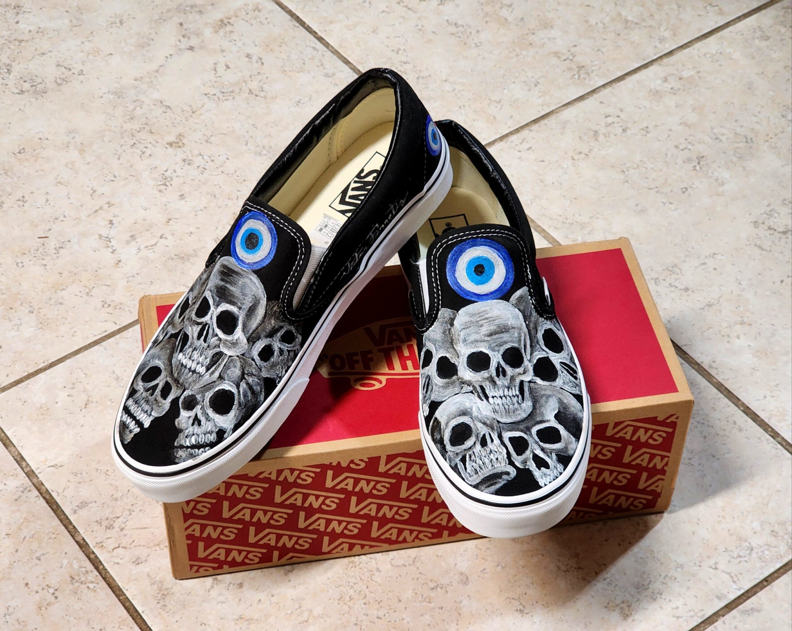 Brand New Vans | Handpainted Design of Skulls and evil eye. The artist signed these vans. Textile paint. Washer and dryer safe. Size: 10.5 US men | 12 US women