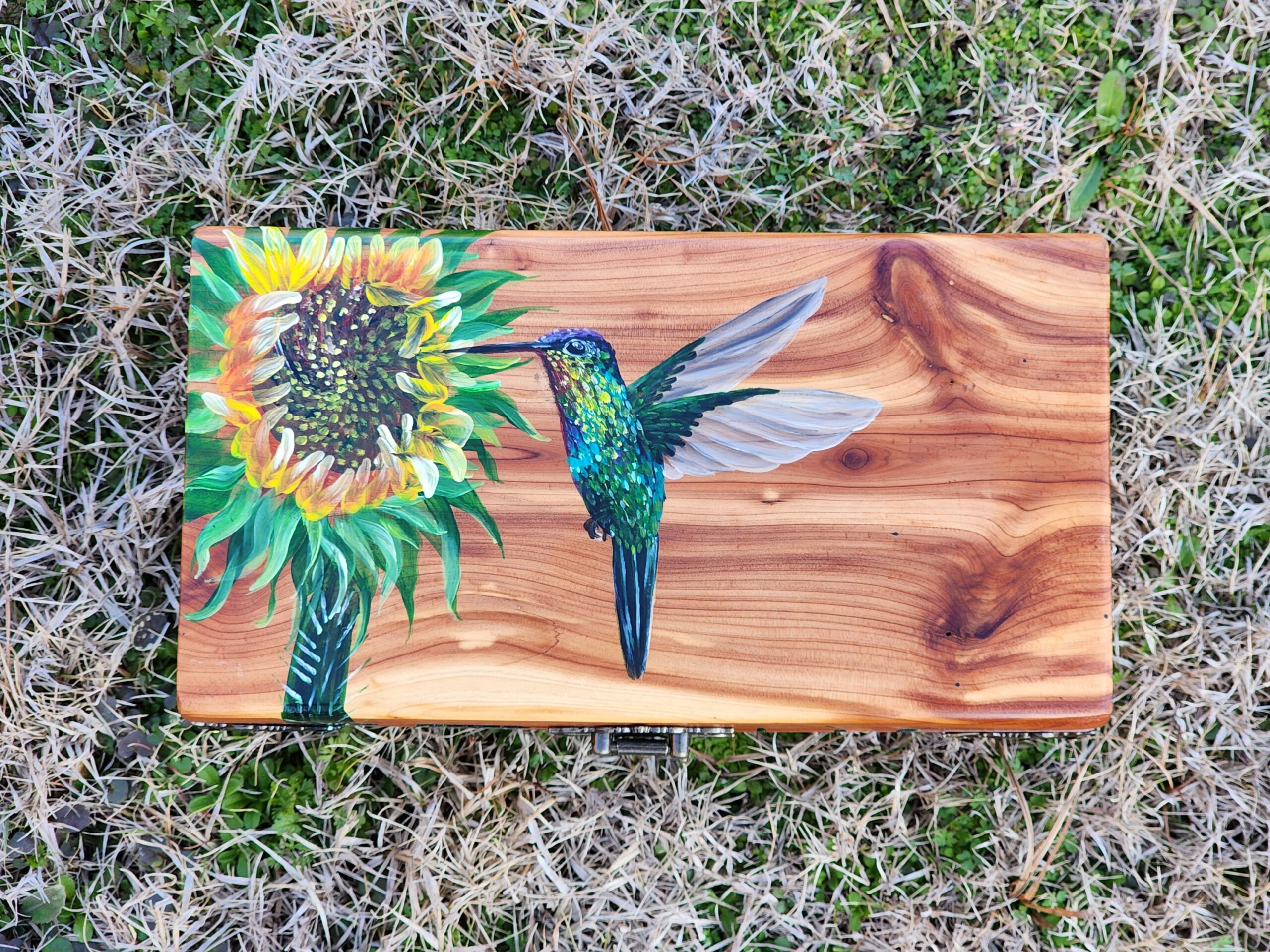 Repurposed antique wooden jewelry box. Handpainted design of a sunflower with a hummingbird. Antique bronze plated clasps and brass corner decorations.