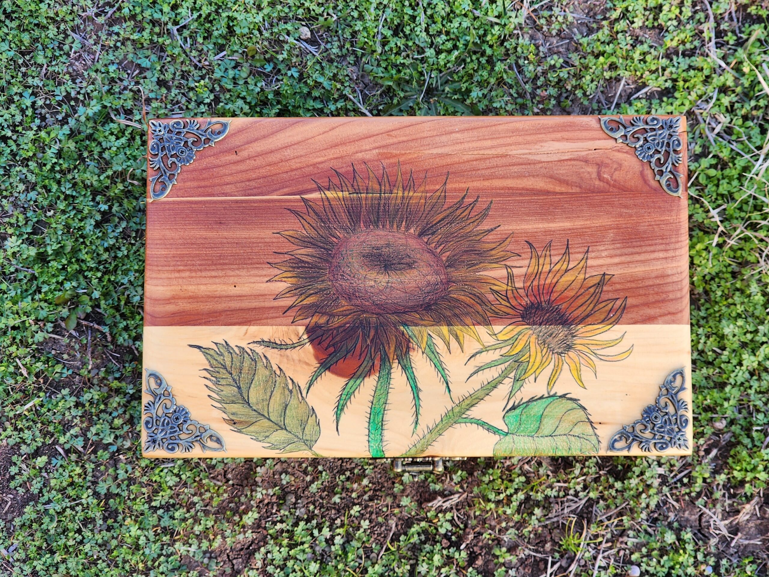 Repurposed antique wooden jewelry box. Handpainted design of a sunflower drawn with graphite and color pencils. Brass feet and antique bronze plated clasps.