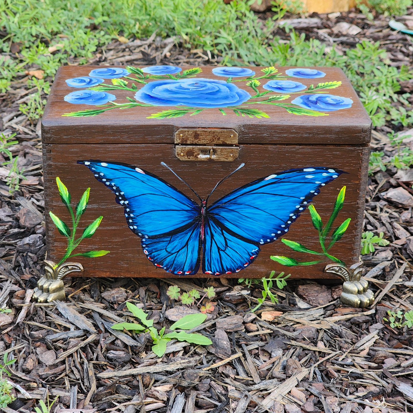 This is an antique cigar box that was repurposed into a beautiful jewelry box with a blue morpho butterfly and blue roses.