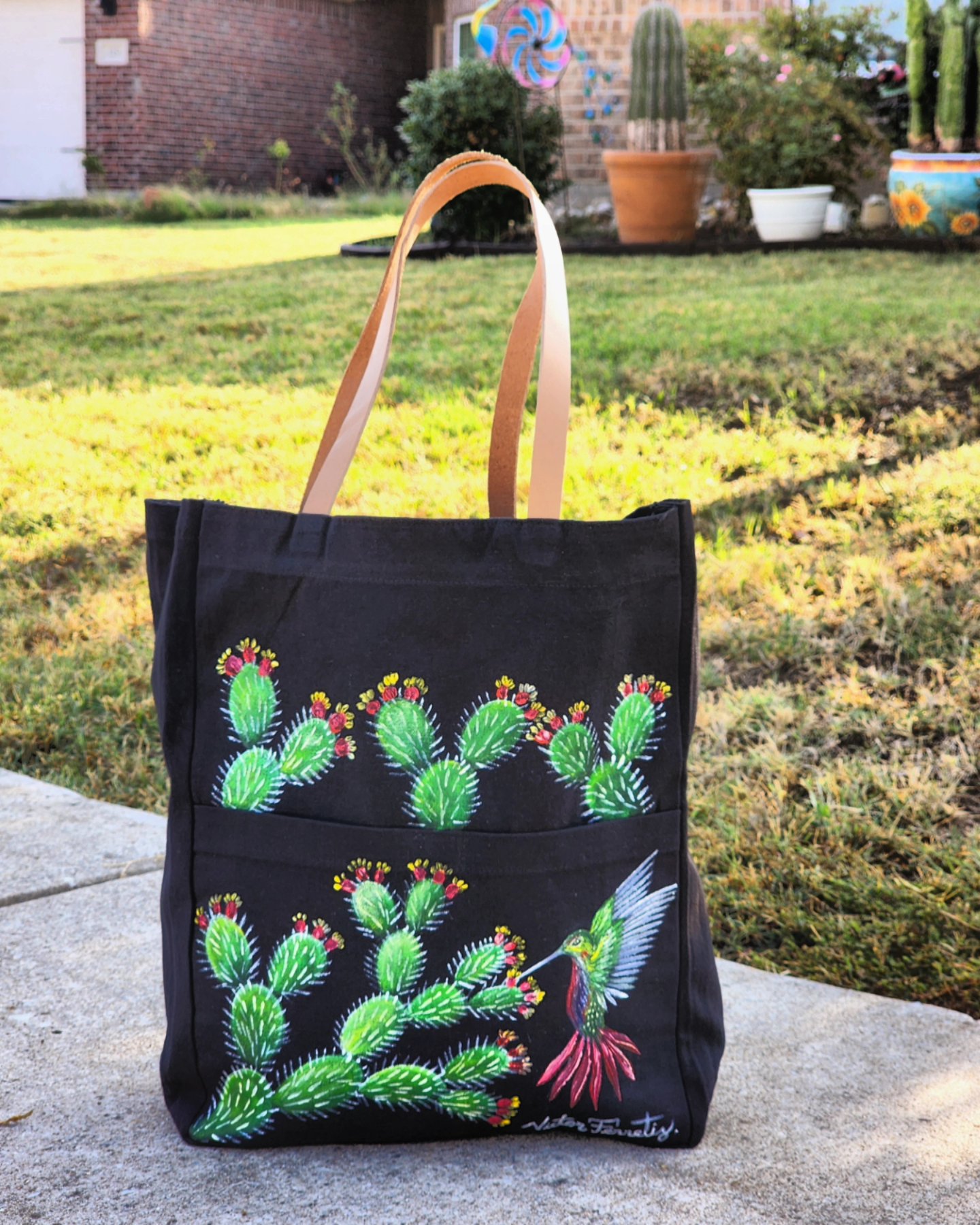 This is a handpainted black tote bag with resistant leather handles. This bag was painted with textile paint on tote fabric. Size: 12×15 inches. Washer and dryer safe.