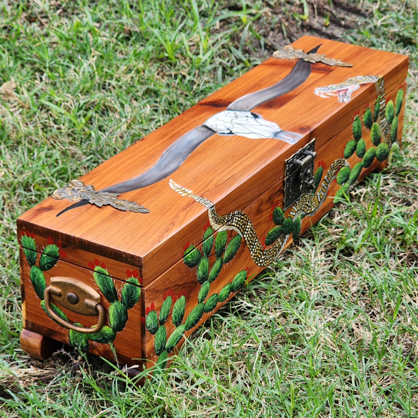 Repurposed antique wooden box into a watch box. The box has a detailed design of a longhorn skull over cacti and a rattle snake. The box is made of cedar wood. Real dimensions of box in inches: 4 length x 17 width x 4.5 height.