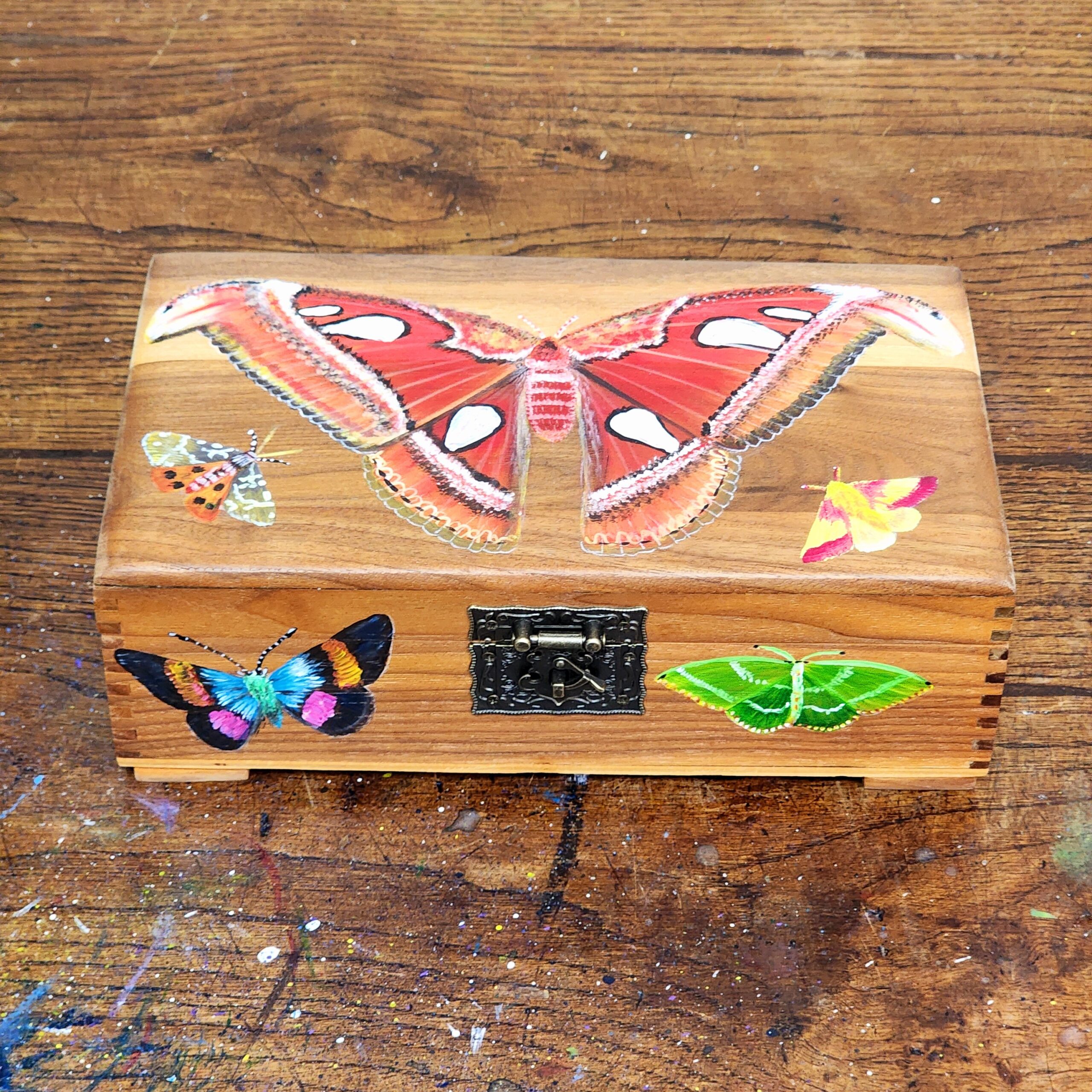 Repurposed antique wooden jewelry box with original design of moths.