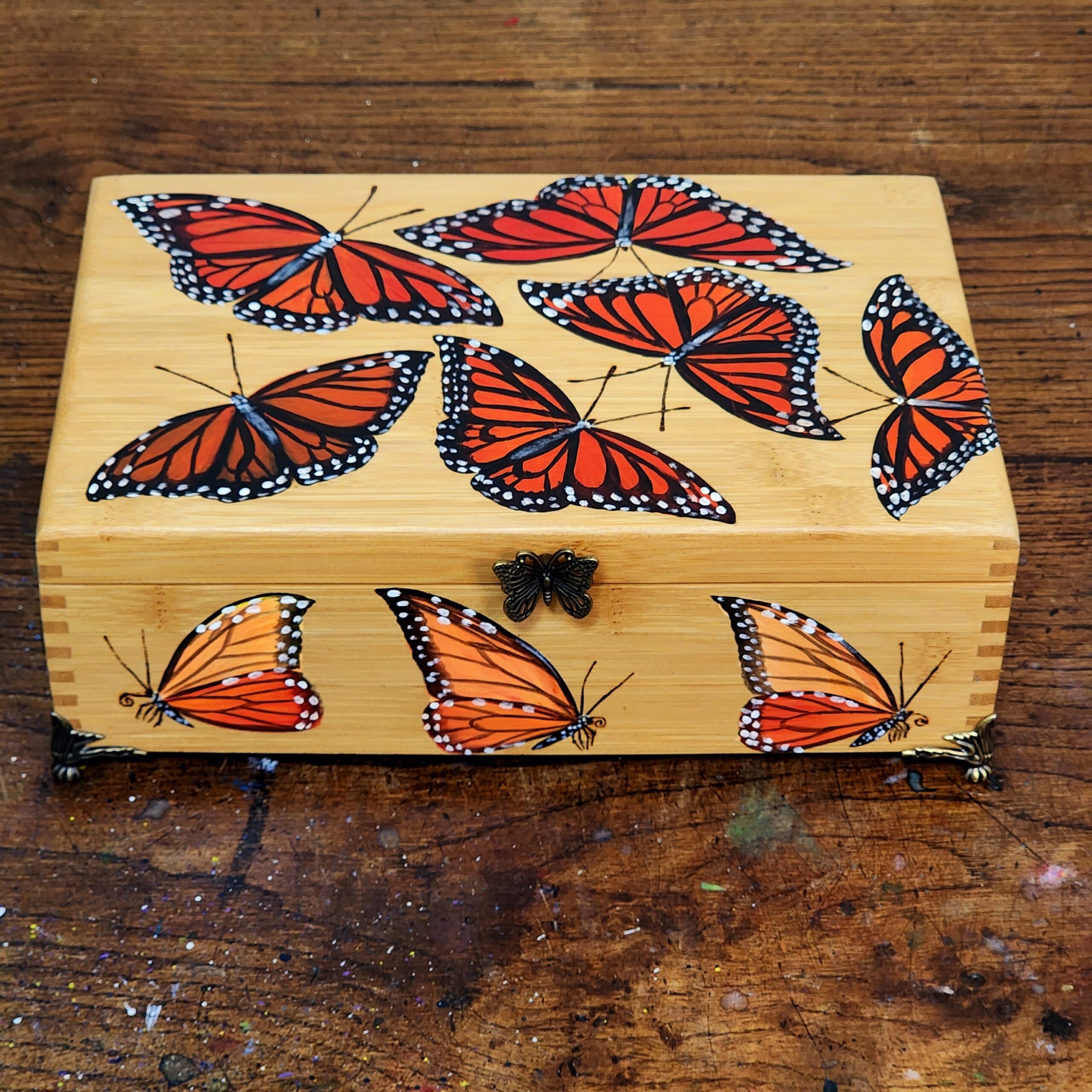 Antique bamboo box repurposed into a trinket/jewelry box with design of some monarch butterflies. Bronze plated clasps and corner decorations added with brass feet.